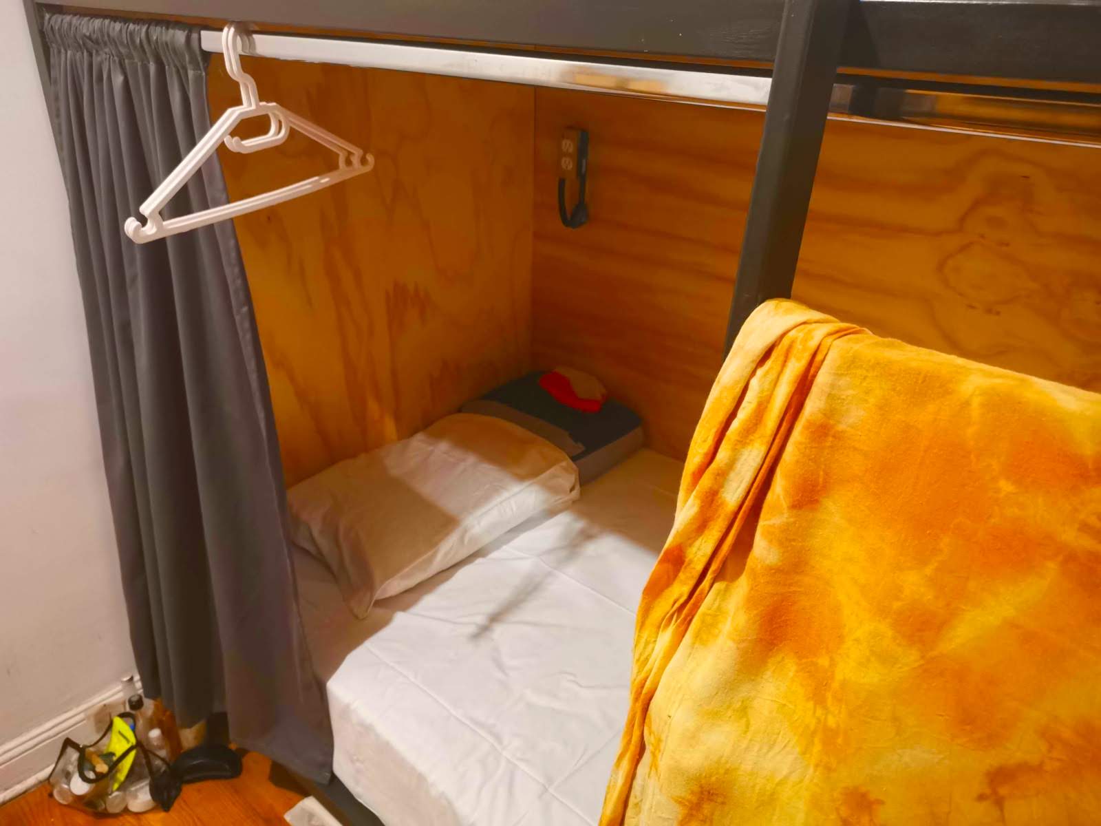 Bunkbed with white bed linen and a grey curtain.