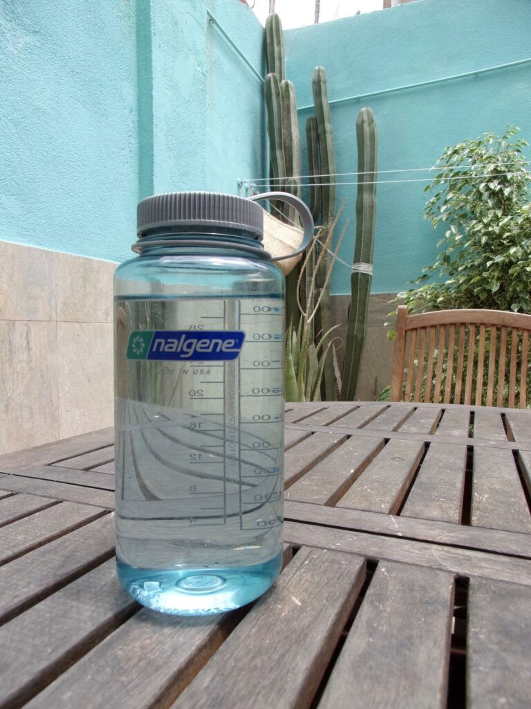 A 1 liter water bottle on a table - a sustainable way to travel cheap