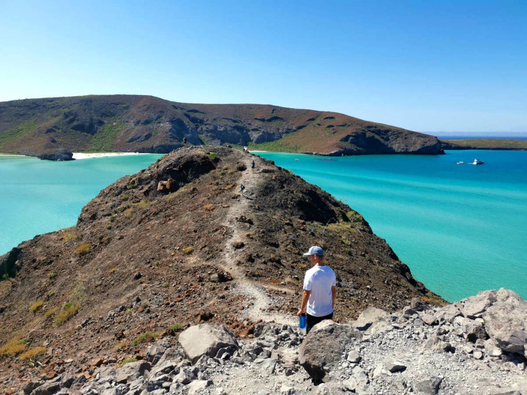 Allan walking on rocks at Balandra Bay, La Paz, Mexico where he traveled to super cheap.