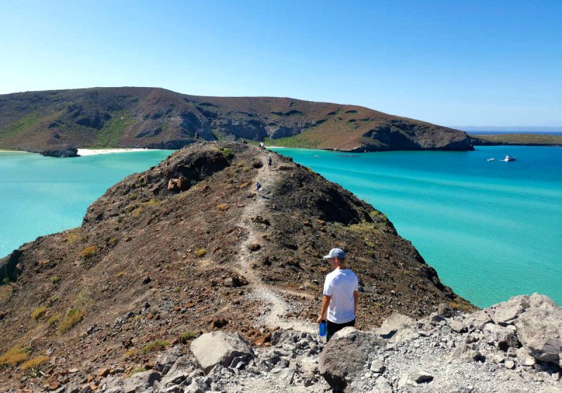 Allan walking on rocks at Balandra Bay, Mexico where he traveled to super cheap.