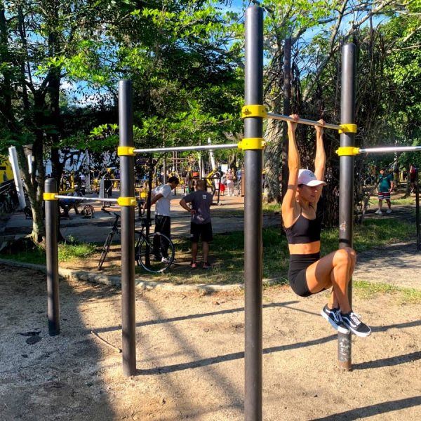 Katharina hanging from a bar in a free workout park - one of our favorite ways to stay fit while traveling!