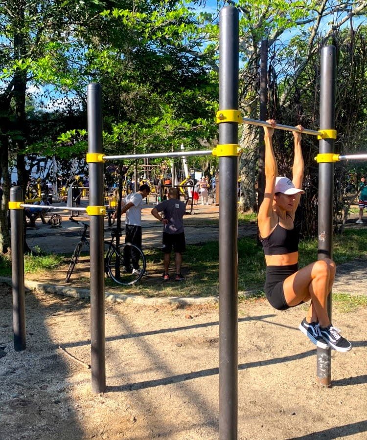 Katharina hanging from a bar in a free workout park - one of our favorite ways to stay fit while traveling!