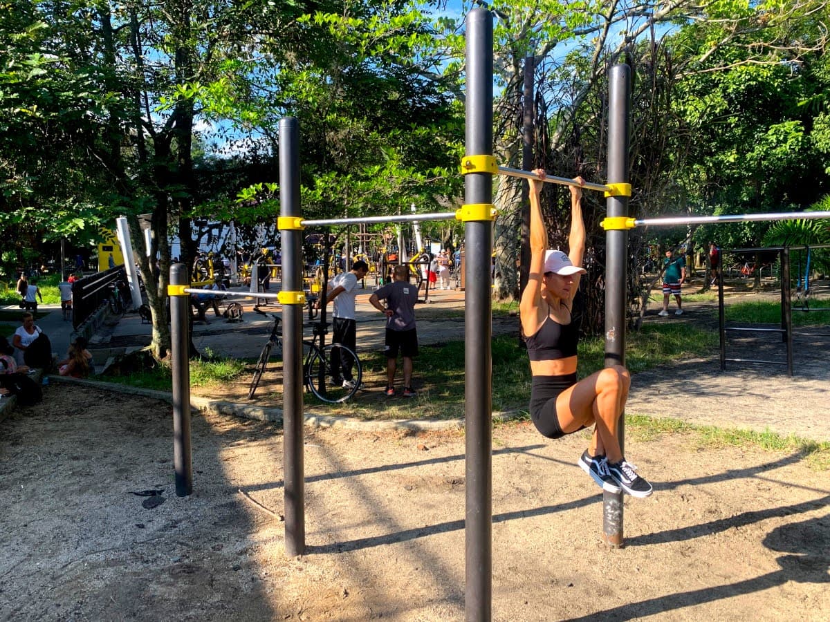 Katharina hanging from a bar in a free workout park - one of our favorite free ways to stay fit while traveling!