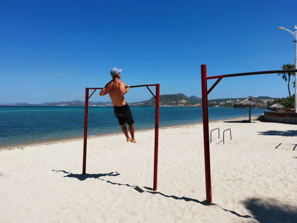 A man in a blue hat on the beach working out on the road in Mexico