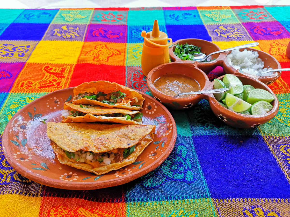Three tacos on a colorful table cloth at Xalisco Birria some of the best tacos in San Miguel De Allende