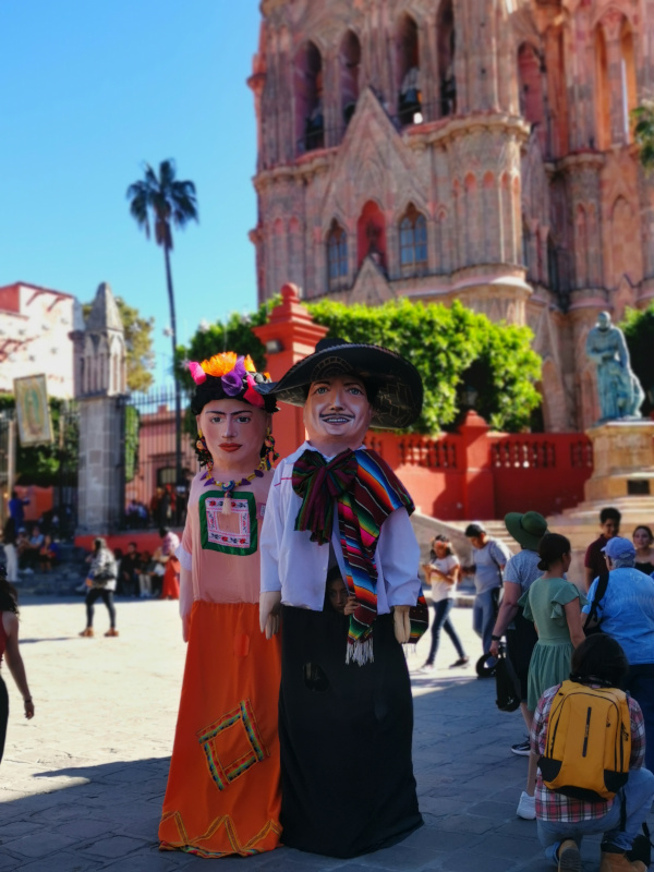 Two people standing in front of a church dressed up in puppet costumes