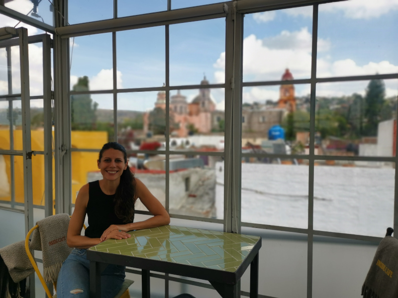Katharina sitting at a table at Inside Cafe with a panoramic view behind her
