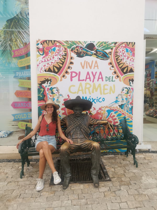 Katharina sitting next to a cowboy statue in the center of Playa del Carmen