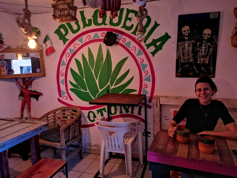 Katharina sitting at a table drinking pulque