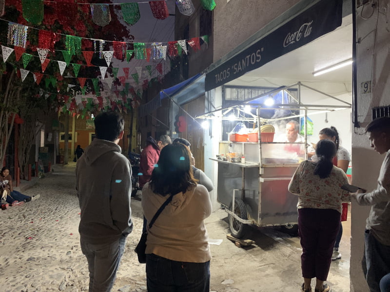 People standing in street waiting for food at Tacos Santos in San Miguel de Allende