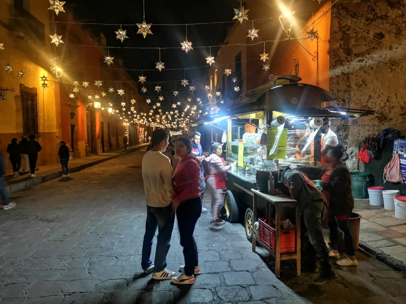 People standing on the street in front of a taco cart waiting for tacos in San Miguel De Allende