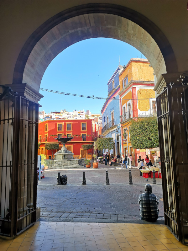 A square with colorful houses viewed through an archway