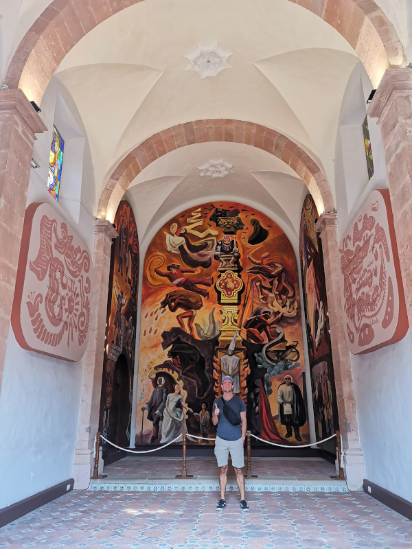 Allan standing in front of a mural at Museo Pueblo del Guanajuato one of the top things to do in Guanajuato.