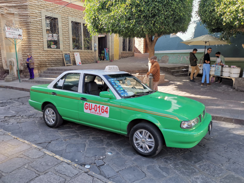 A green taxi driving down the road in Guanajuato