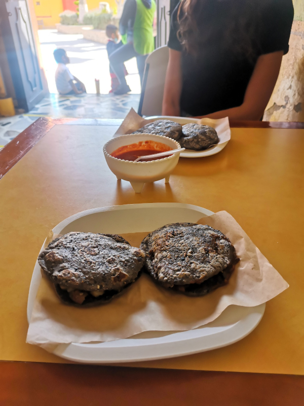 Two blue corn gorditas on a white plate on a table