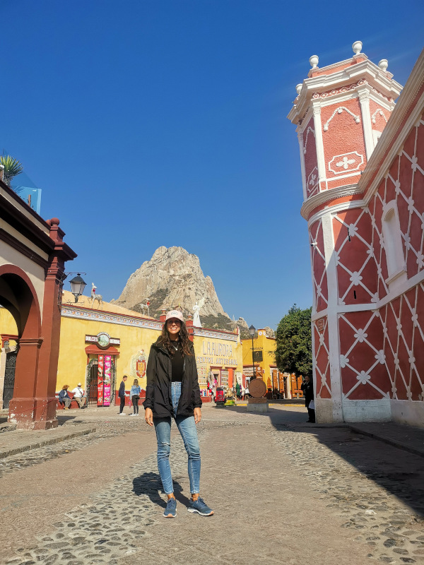 Katharina standing in the middle of a colorful street in Bernal Querétaro with the monolith Peña de Bernal in the background