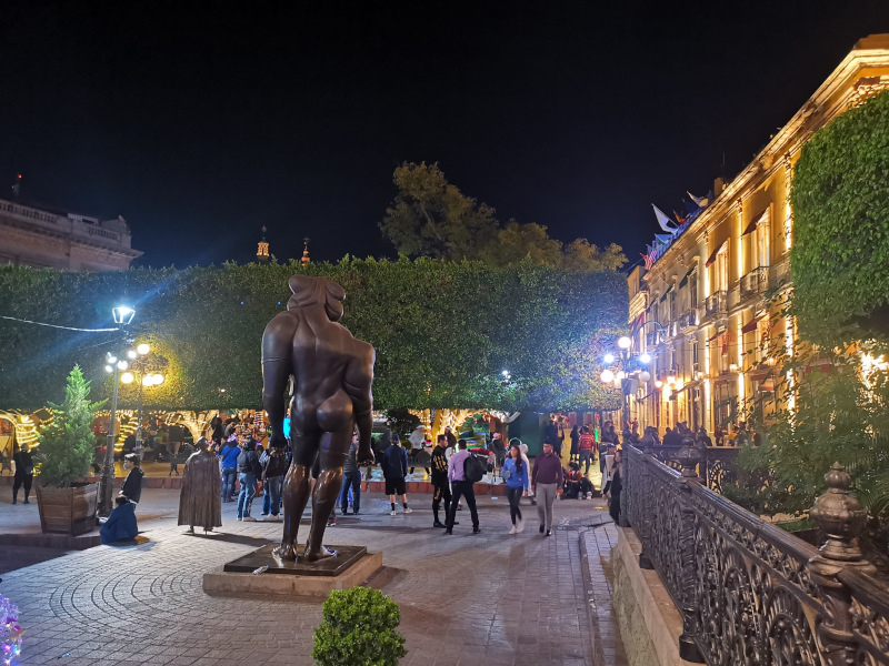 People walking around in Jardin de la Union with an interesting statue in the foreground