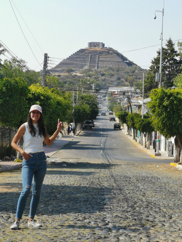Katharina pointing towards the pyramid from the street up the hill