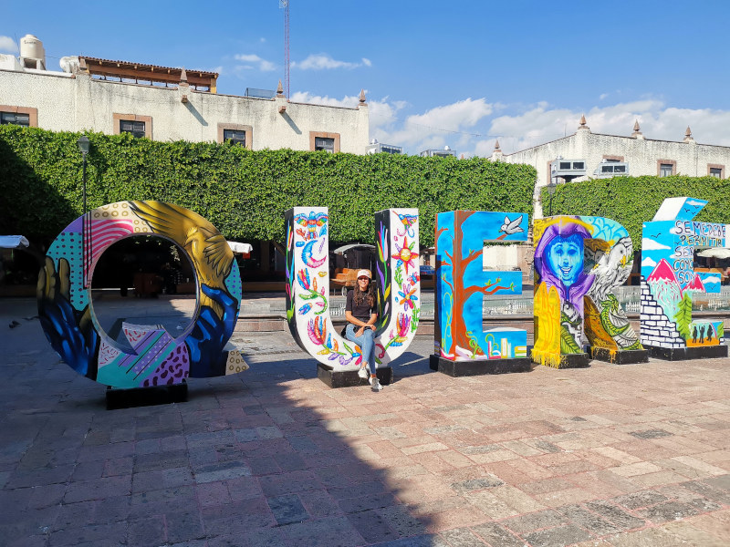Katharina sitting on the colorful Querétaro letters in front of Templo de Santa Rosa