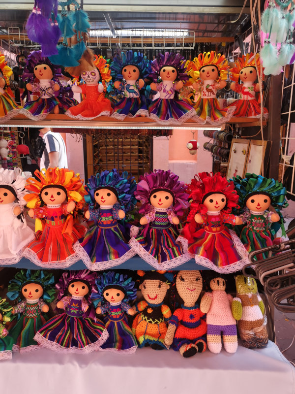 A display of colorful munecas stacked up on shelves