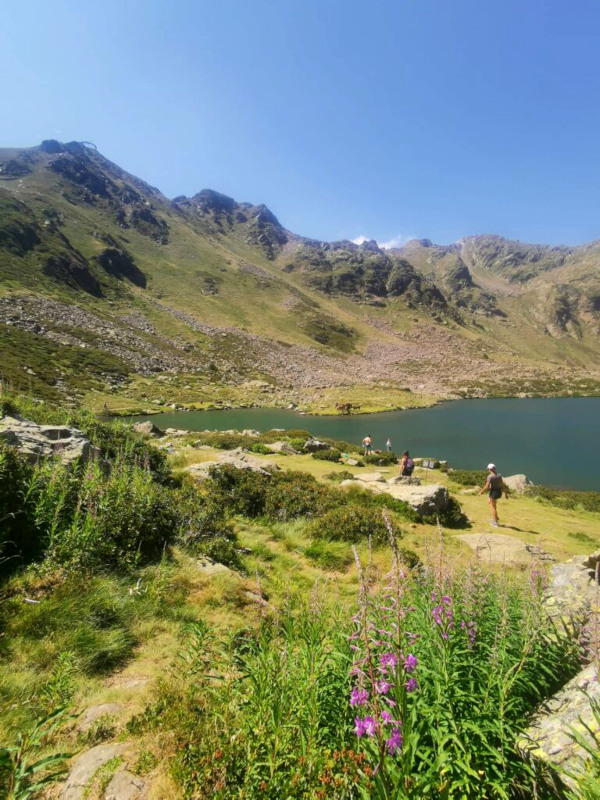 A group of people walking near a lake in the mountains of Andorra