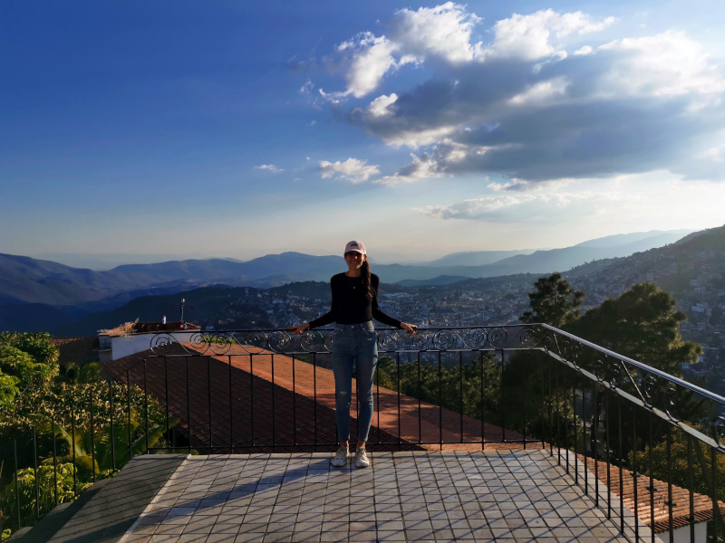 Katharina standing on the edge of Hotel Montetaxco's balcony with hills and the City of Taxco in the background