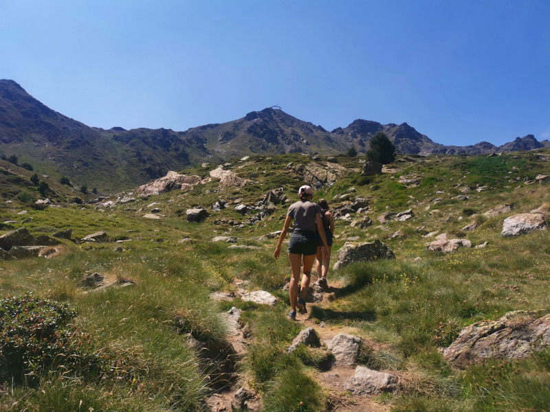 Two woman walking up a grassy hill on a hike in Andorra