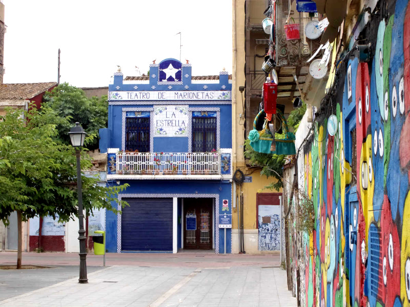 A blue building next to a colorful wall