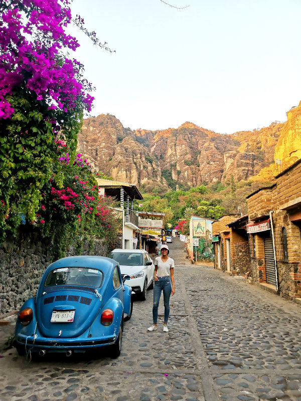 Katharina standing in front of Tepoztlán's rocky mountains and next to a blue VW