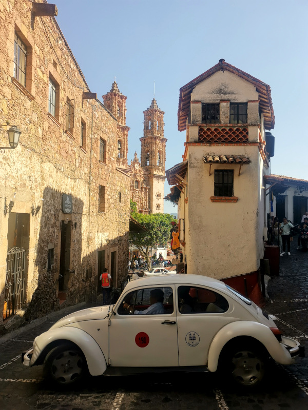 A white VW trying to get around a corner in Taxco's narrow streets