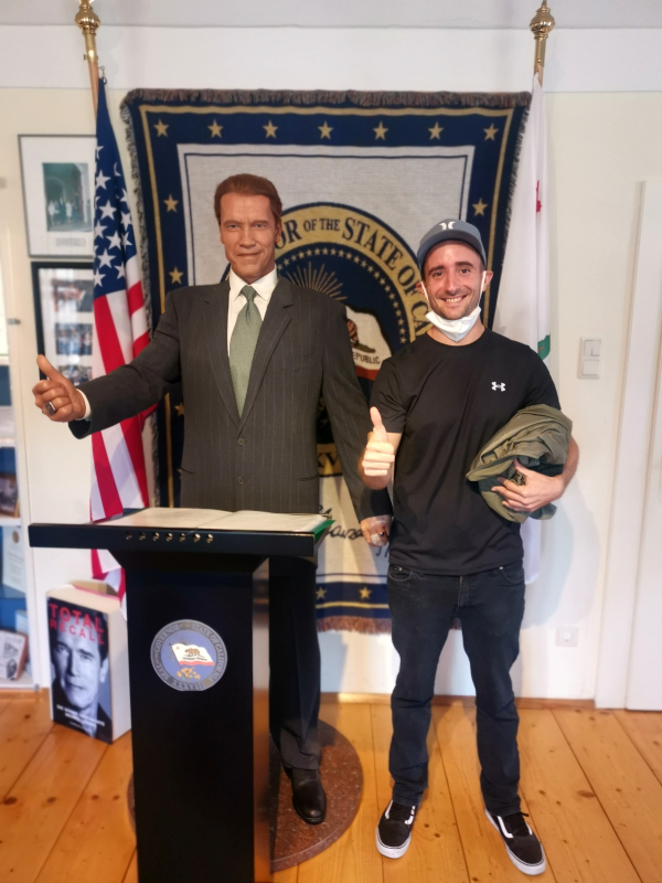 Allan standing next to a wax statue in the shape of Arnold Schwarzenegger 