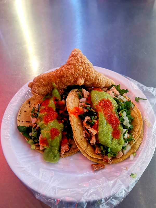 Two carnitas tacos with chicharron on a plate