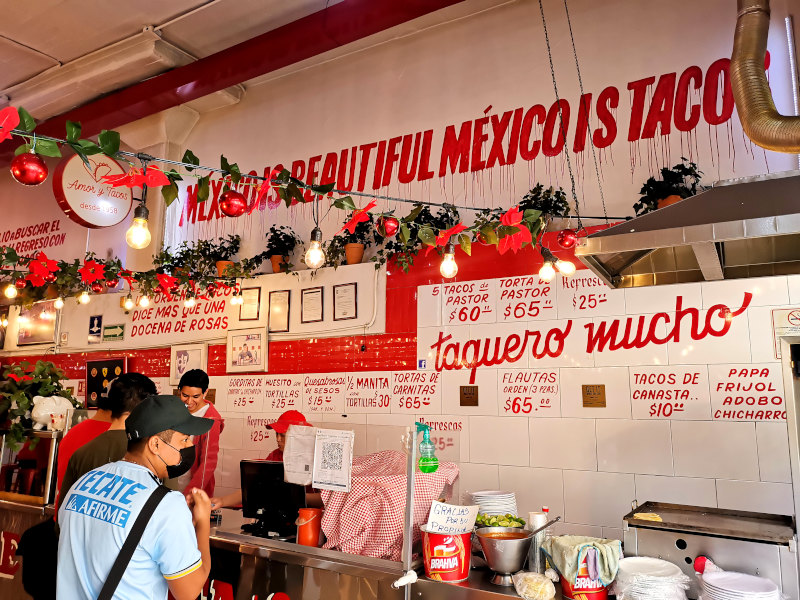 A colorful taco restaurant in Mexico City with interesting slogans written all over the wall