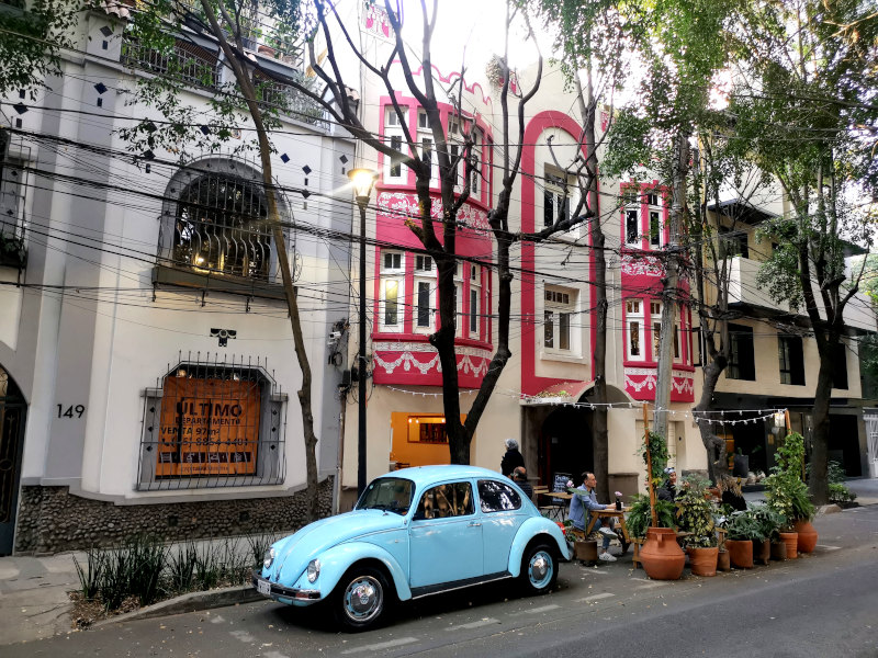 A blue volkswagen parked outside a cafe in mexico city