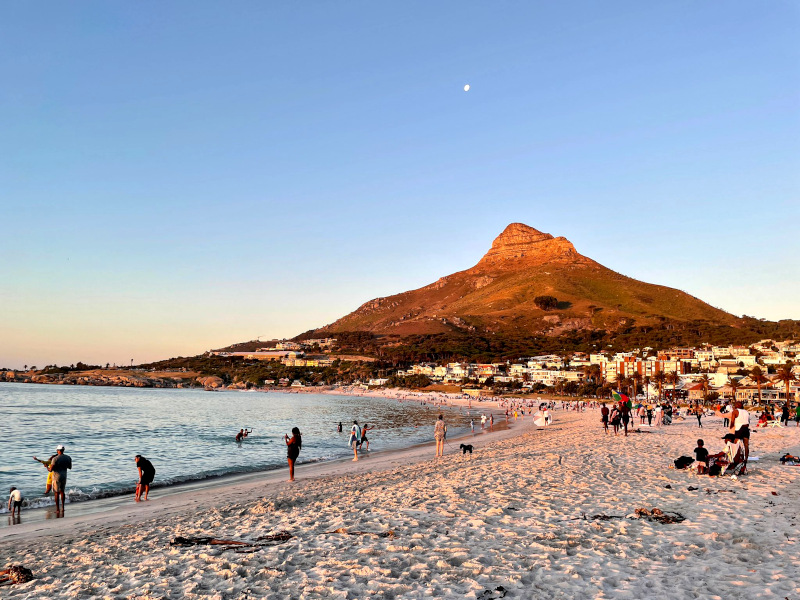People enjoying sunset on the beach at Camps Bay in South Africa with Lion's Head in the background