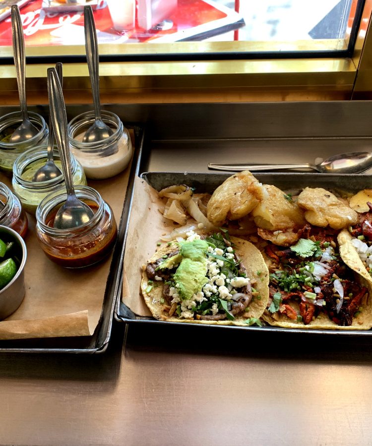 A selection of the best tacos in Mexico City on a tray with salsas next to it