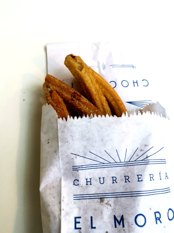 A paper bag with churros poking out