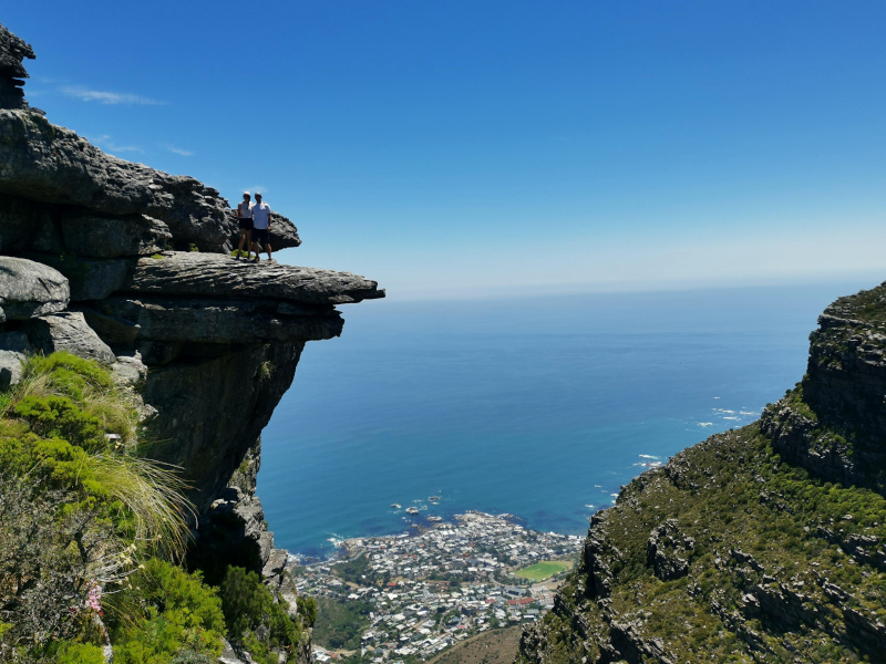 Two people standing on a large rock formation with an ocean view on the Kasteelspoort hike in Cape Town