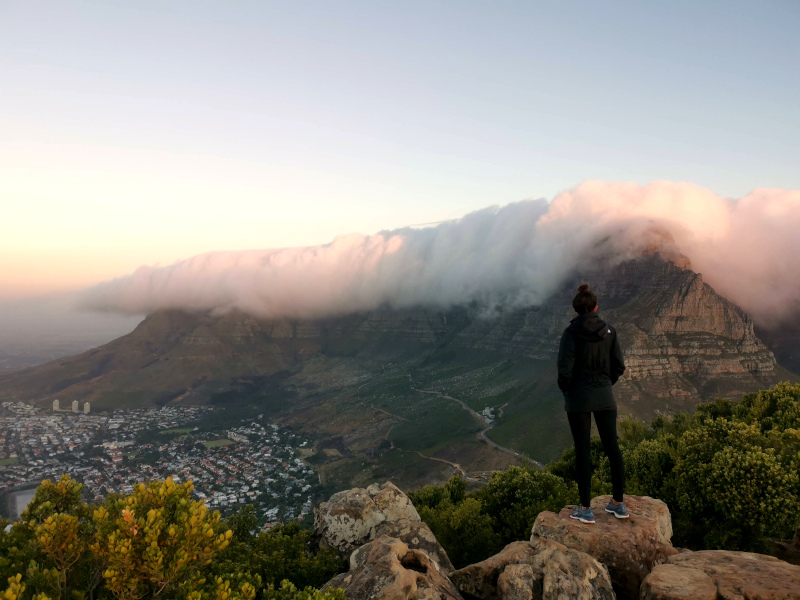 Katharina standing on the top of Lion's Head at sunset watching clouds gathering on top