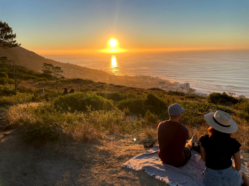A couple sitting enjoying the sunset on Signal Hill one of the many fun activities in Cape Town