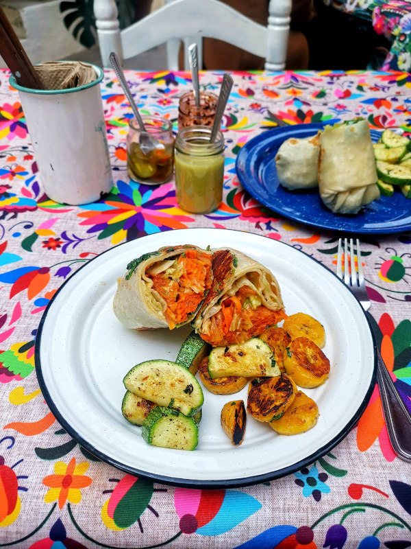 A wrap filled with veggies on a colorful table cloth