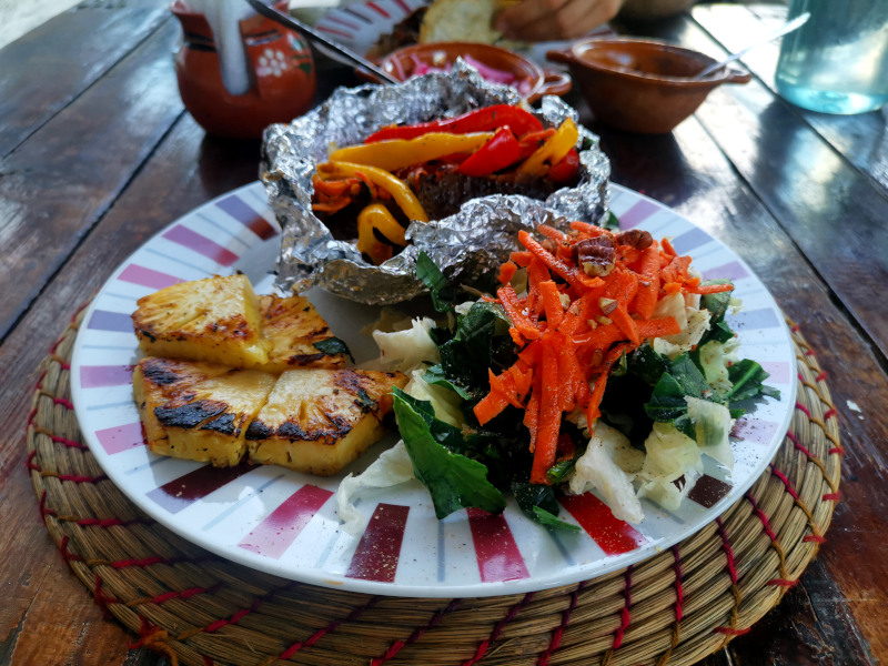 A plate of baked potato, grilled pineapple, veggies and salad at Zenzontle 