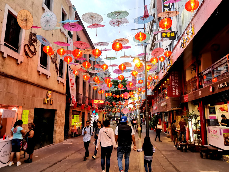 Families going for a walk under orange lanterns in China town