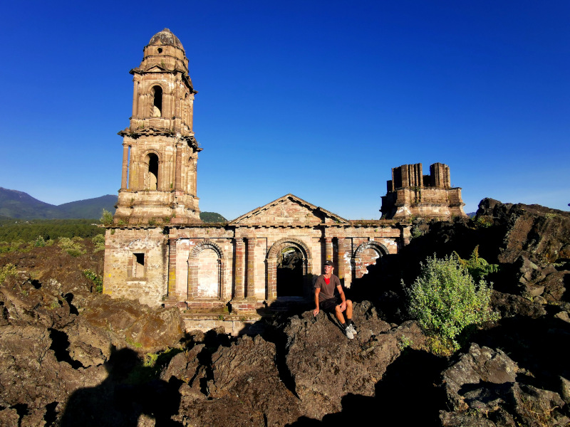 Allan sitting on some rocks in front of the San Juan de Parangaricutiro church