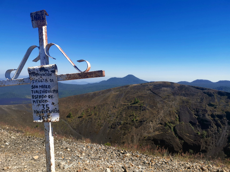 Cross at the summit of Paricutin with the crater of the volcano in the background