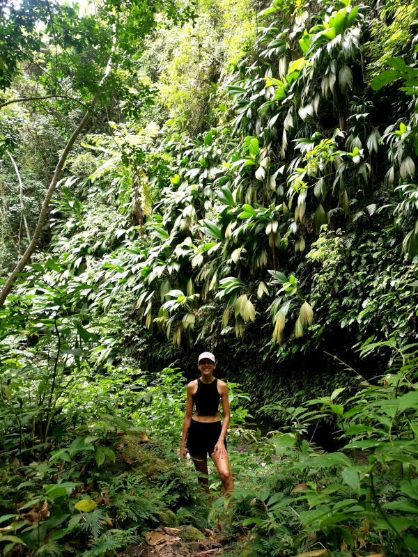 Katharina standing on a path surrounded by green jungle leaves