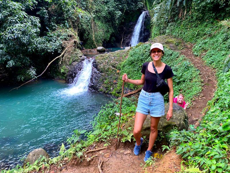 Katharina standing in front of the first Seven Sisters Waterfall with a walking stick
