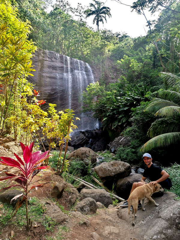 Allan sitting with a dog in front of Mt Carmel's first waterfall - one of the best waterfalls in Grenada