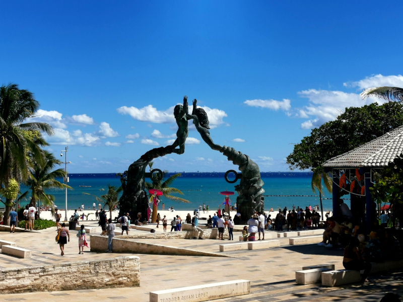 Statue near the beach in playa del carmen with groups of tourists underneath