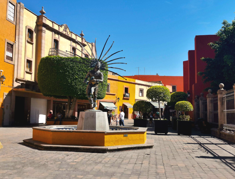 A statue in front of colorful houses in Querétaro